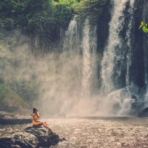 Beautiful woman sitting near waterfall enjoying the sun, Phnom Koulen at Siem Reap, Cambodia